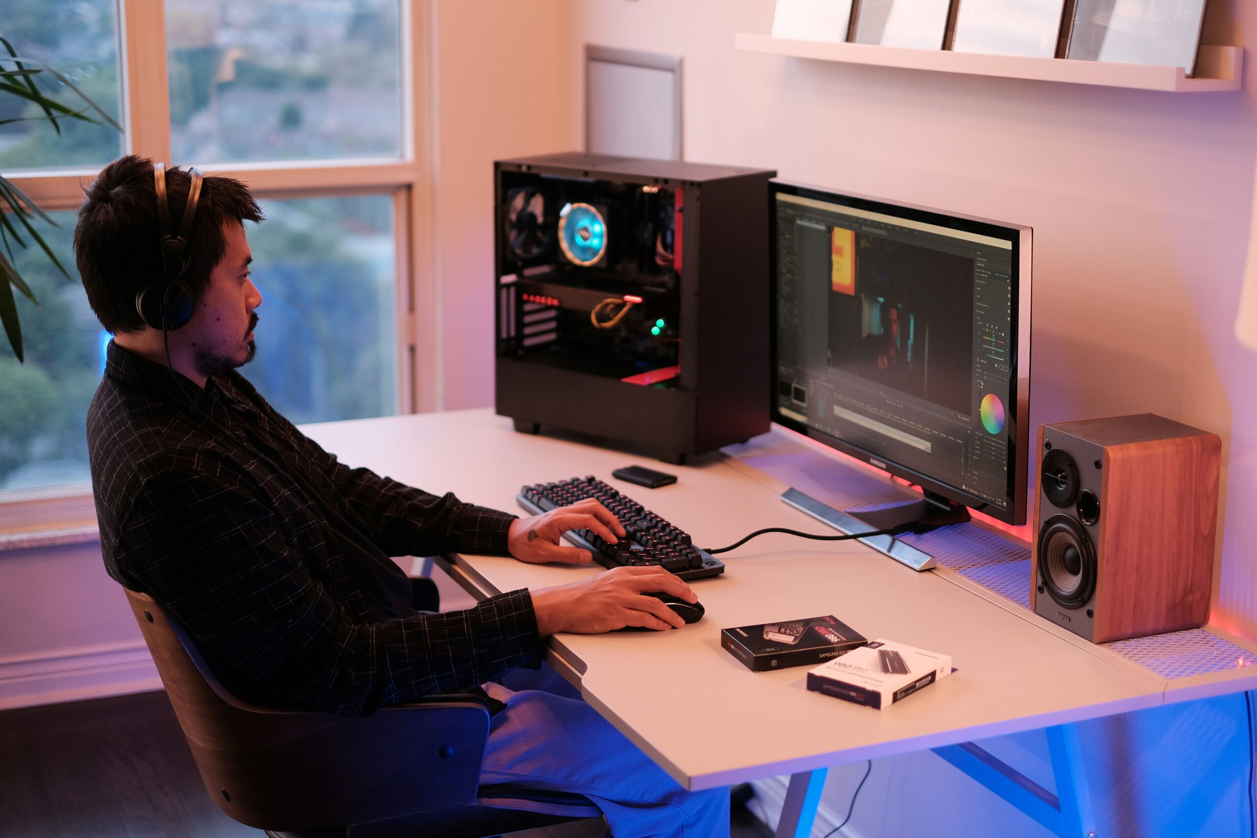 a person sitting at a desk with a computer and speakers